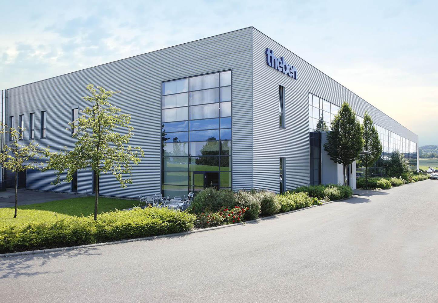 Ansicht Theben Produktionsgebäude von Außen -  mit Sitzgruppe und Grünanlage